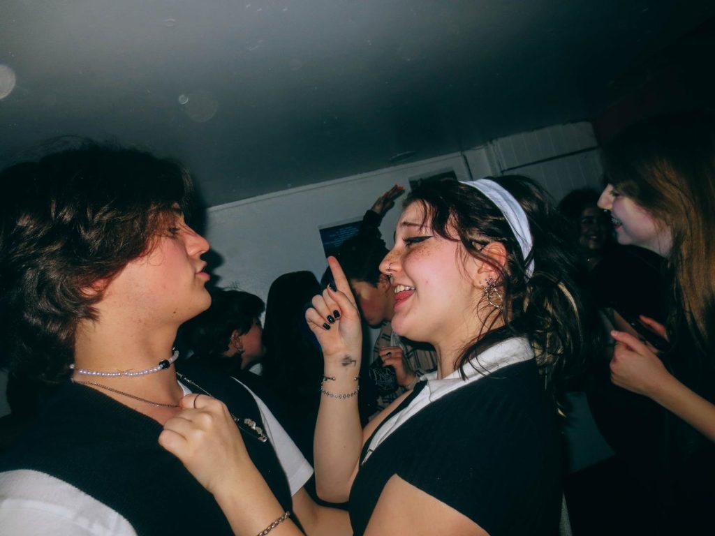 A young couple sing along to early-2010s music at a Tumblr themed party